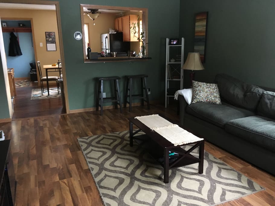 Living room includes kitchen bar area, record player, and mounted wall TV.