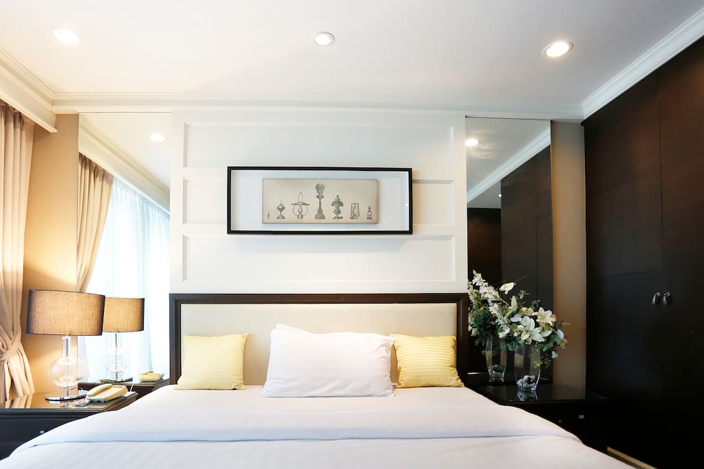 Spacious master bedroom with wall mirrors on both sides of the bed
