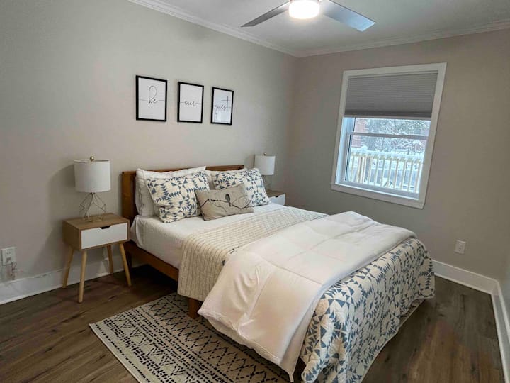 Habitación de invitados con cama tamaño queen con armario y vistas al río desde ambas ventanas. 