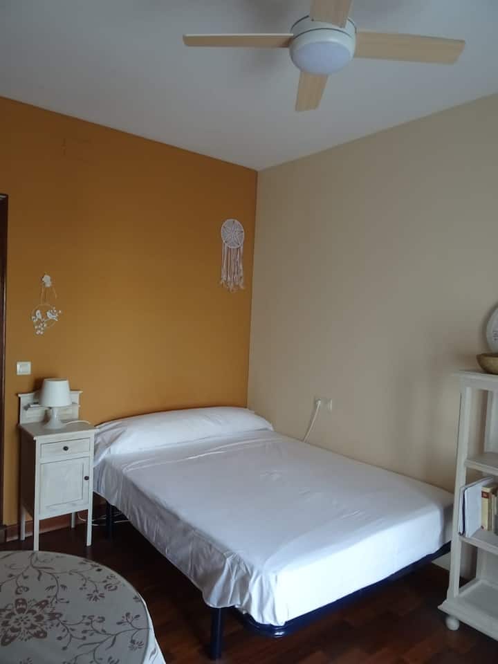 غرفة إستر، سرير مزدوج ومروحة على السقف. شرفة بإطلالة على حمام السباحة