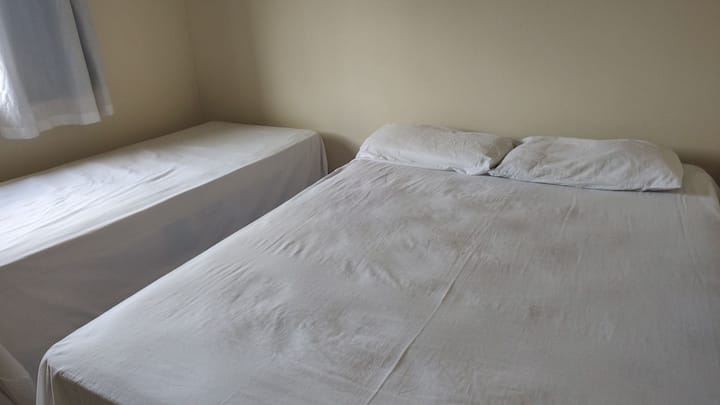 Спална соба со тавански вентилатори и два кревета, еден брачен и еден единечен .