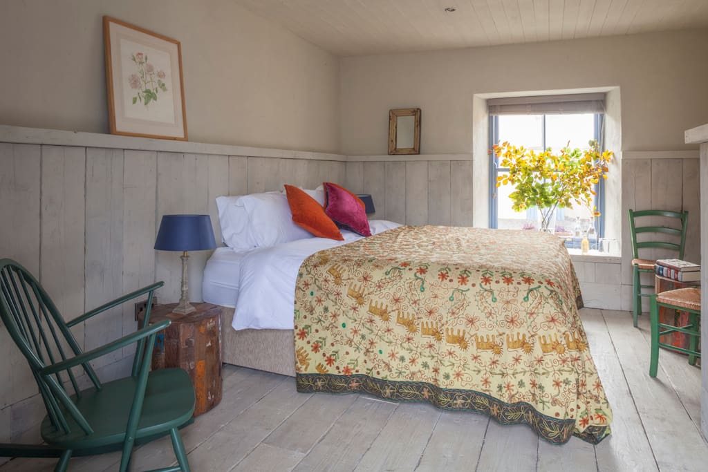 The Ploughman's Room, with bright, south facing window, reclaimed panelling and superking size bed. Each room is ensuite with crisp white linen, smart bathroom, local handmade bath products, a superking sized bed and its own private entrance onto the sunny courtyard - through a cute stable door.
