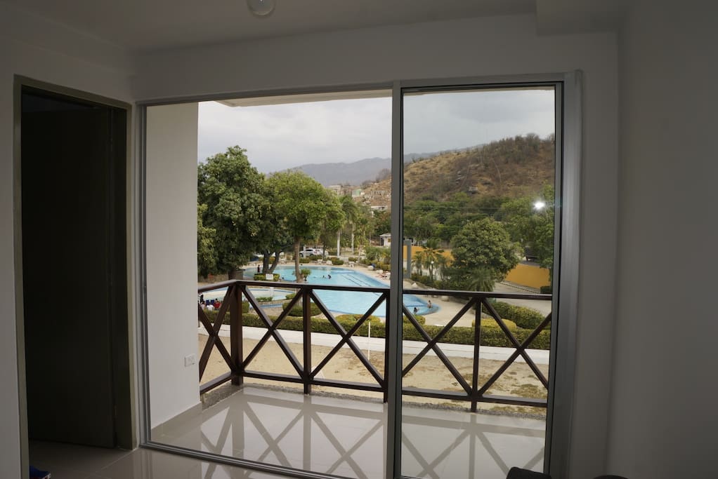 Vista desde la sala hacia el Balcón e interiores del condominio (Piscina)
