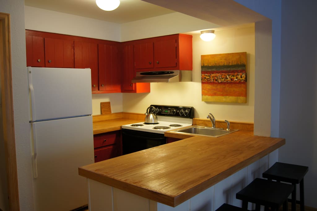 Kitchen with wood countertops and full-size stove and refrigerator.