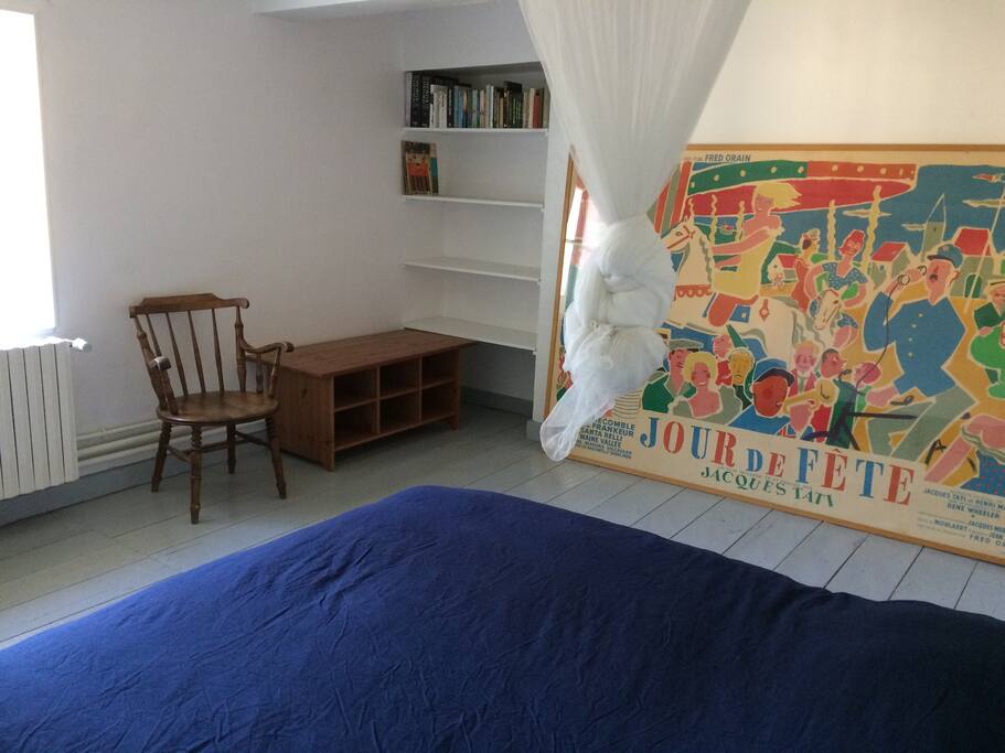 The room has a desk and shelves for clothes