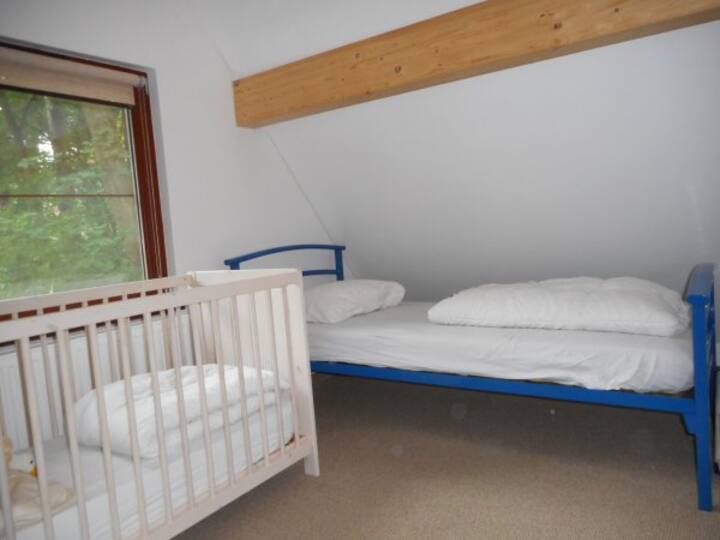 Tweede slaapkamer boven, met twee eenpersoons bedden en een ledikant.