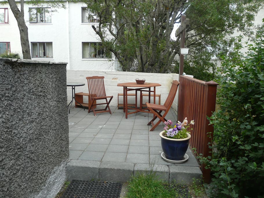 Going past the stairs is a lovely garden terrace with furniture and a grill