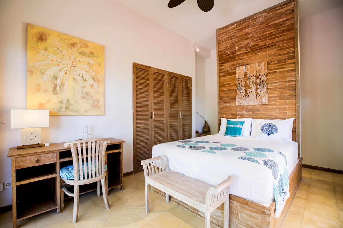 Dettagli della camera da letto, arredati con letto matrimoniale, scrivania e guardaroba, aria condizionata e ventilatore a soffitto. Dispone di un proprio bagno.