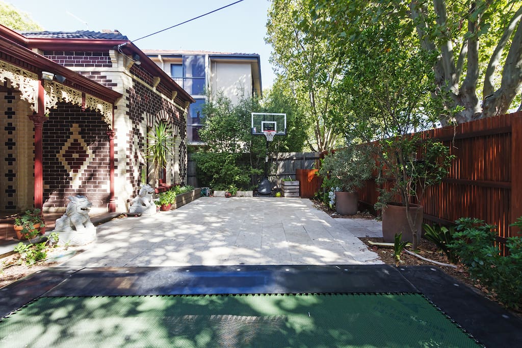Travertine courtyard with trampoline and basketball hoop on leafy street