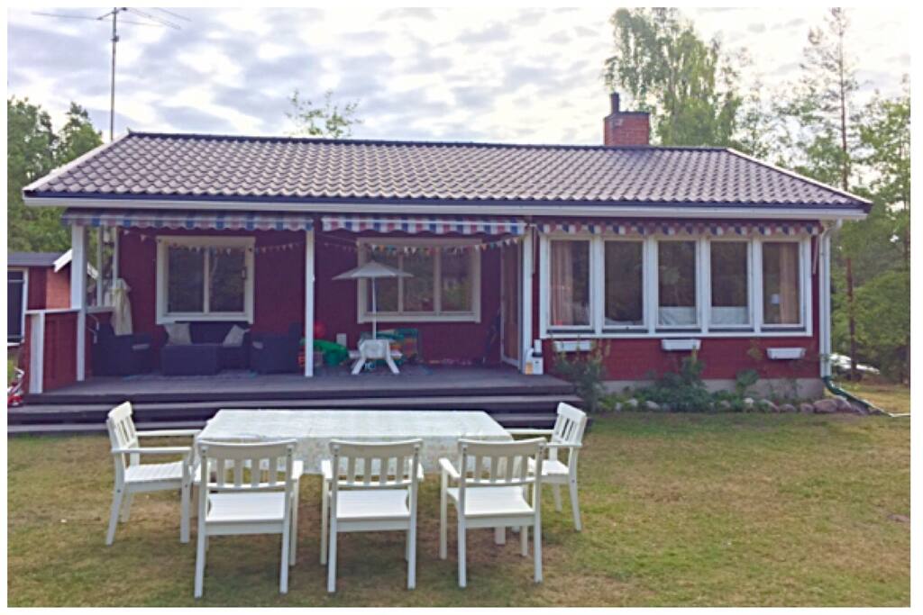 View from the garden. Livingroom to the right, dining area in the middle and the double bedroom to the left.
Outside table and seats. Sofa group under roof and smaller eating table for kids.