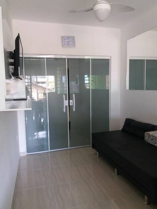 Sala com sofá cama, cama extra, ventilador de teto e tv