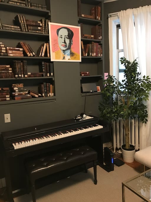 The living room features a piano, a library of vintage books and a Bose sound dock that is compatible with all iPhones.