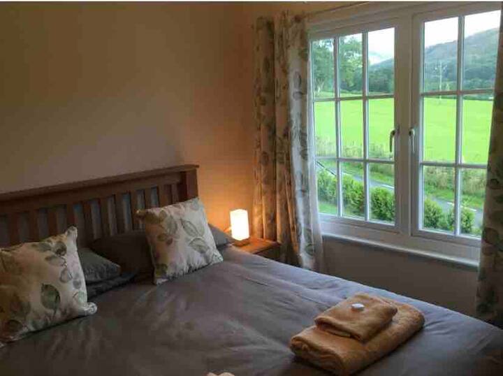 חדר שינה ראשי המציג את הנוף עם מיטת קינג סייז, ארון בגדים גדול בחינם, שידת מגירות, כיסא, מראה וטלוויזיה גדולה התלויה על הקיר