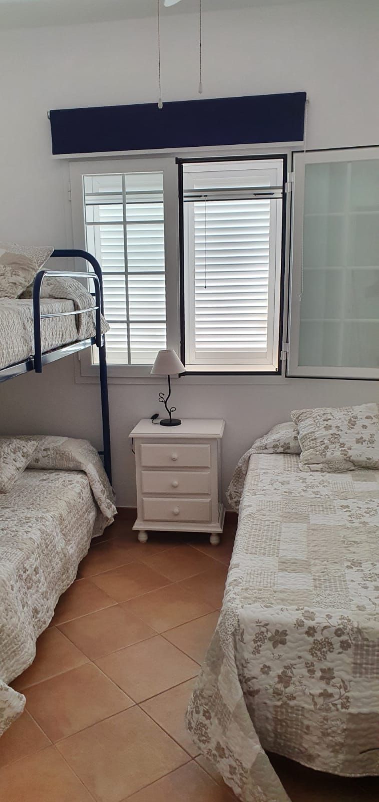 ห้องพักพร้อมเตียงสองชั้นและเตียงหนึ่งเตียงห้องพักมีพัดลมและตู้เสื้อผ้าและมุ้งกันยุง