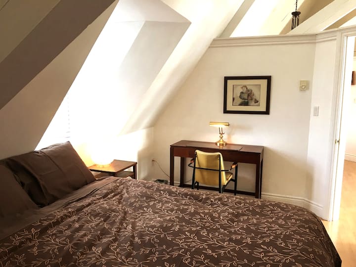 Открита концептуална спалня със сводест таван, удобно двойно легло и чисто спално бельо