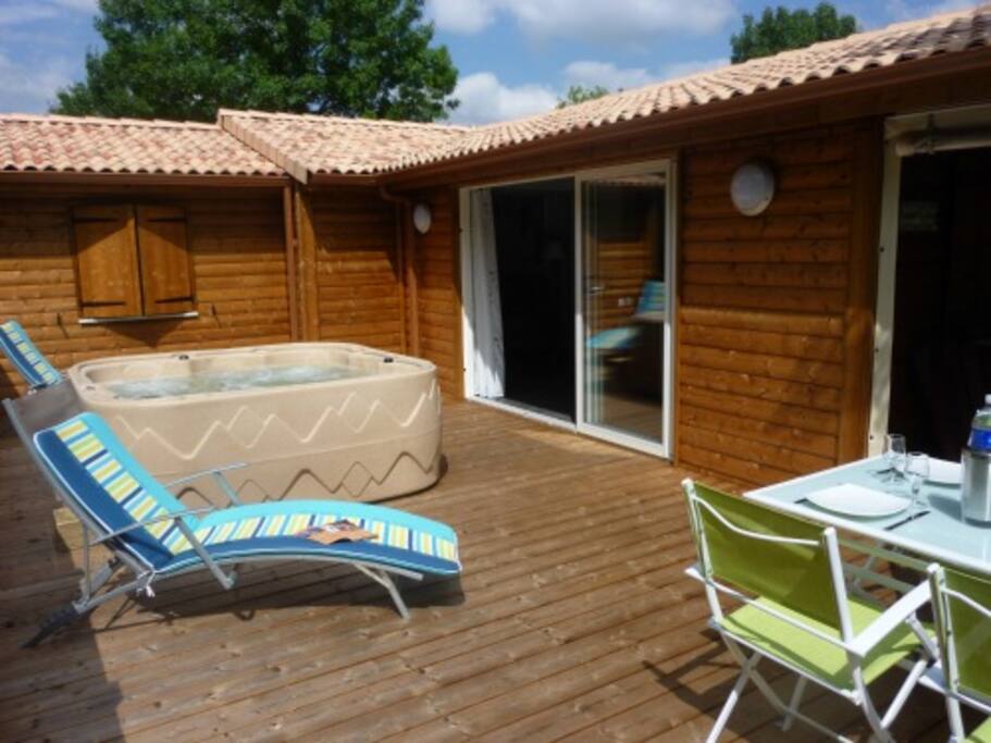 Grande terrasse en bois avec salon de jardin et spa