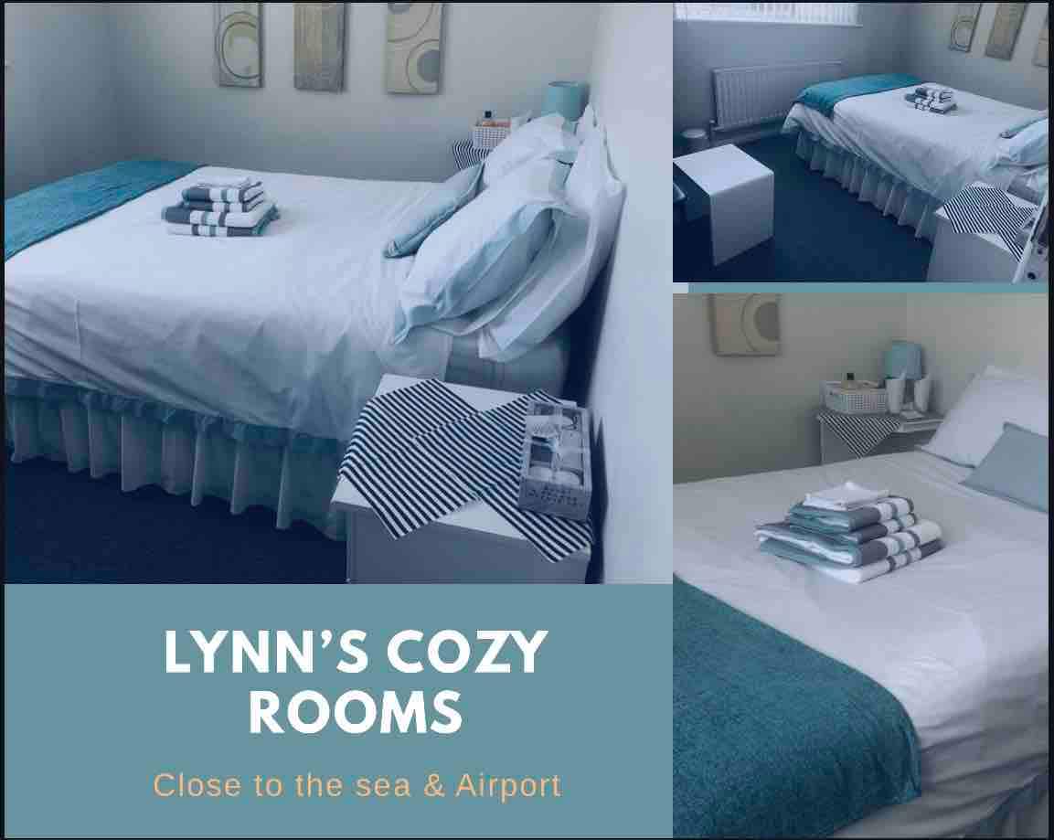 A comfortable sleeping area is presented, featuring a spacious bed with soft blue and white bedding. A bedside table is visible, topped with toiletries and towels. The room is well-lit, with a window allowing natural light to illuminate the space.