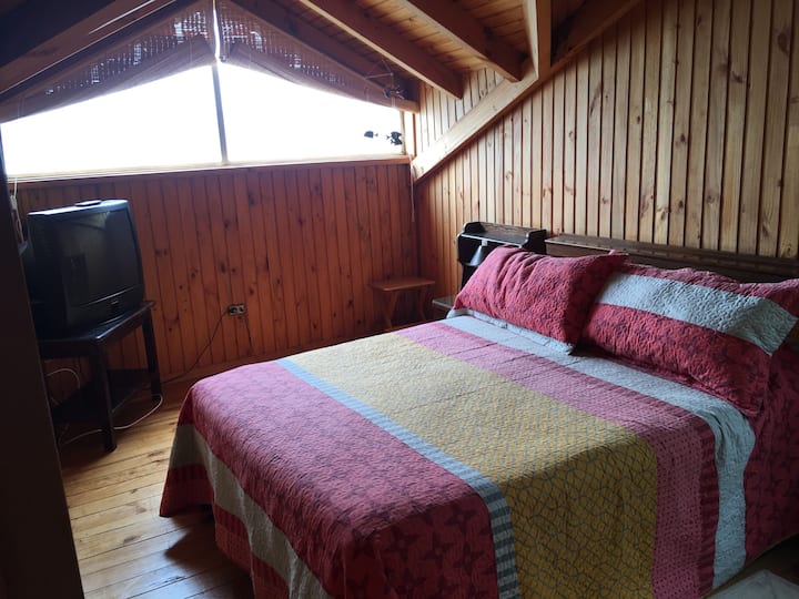 Cálido卧室配有双人床和窗户，可俯瞰太平洋