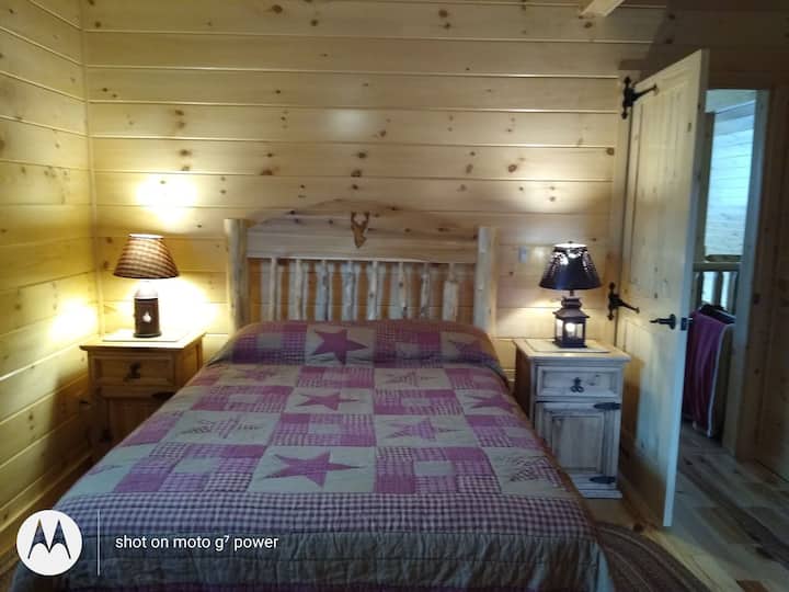 Insulated wall upstairs bedroom behind the loft with double bed, 2 night stands and 3 way lamps and twin bed. Stag deer carved into cedar headboard.
