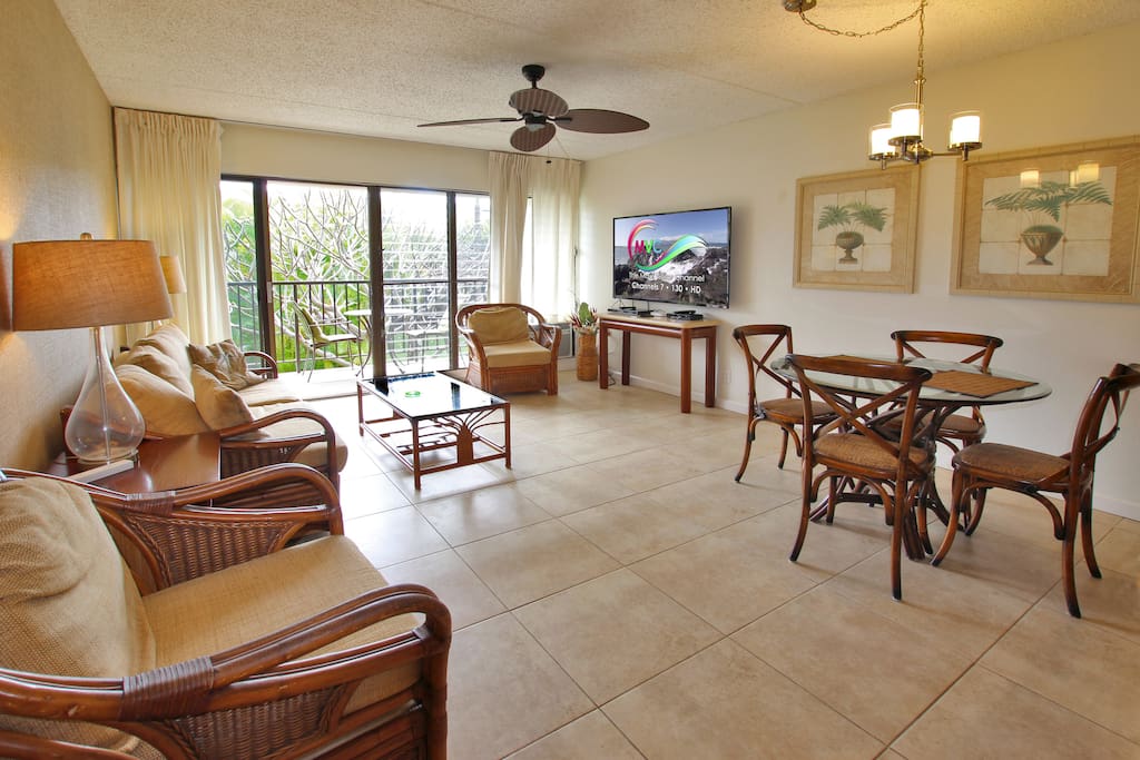 Bright and sunny living room with air conditioner opens up to private balcony lanai with garden view