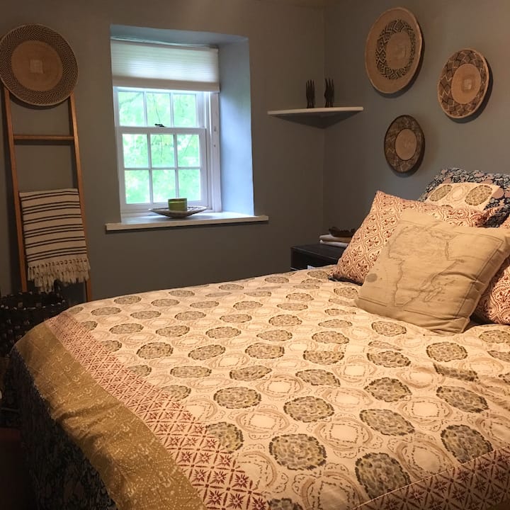 The first guest room has African decor and a firm queen bed with pillow top mattress cover.