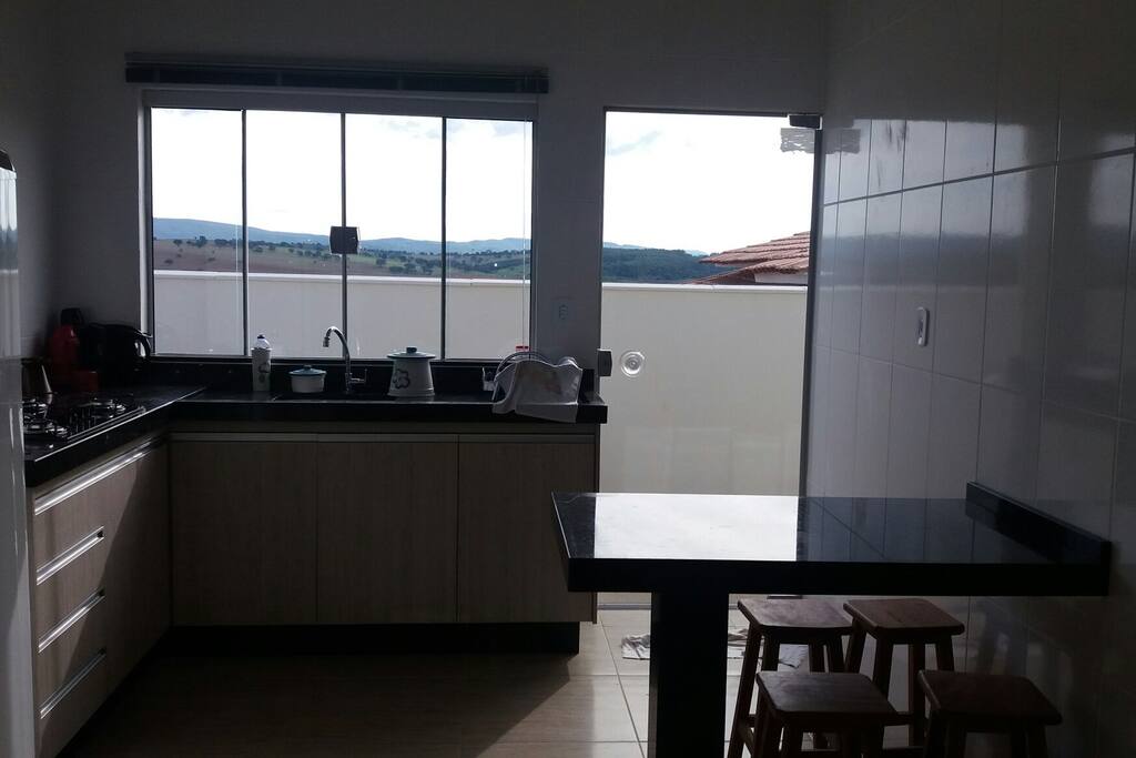 Cozinha equipada com mesa, geladeira, cooktop e armários embutidos.