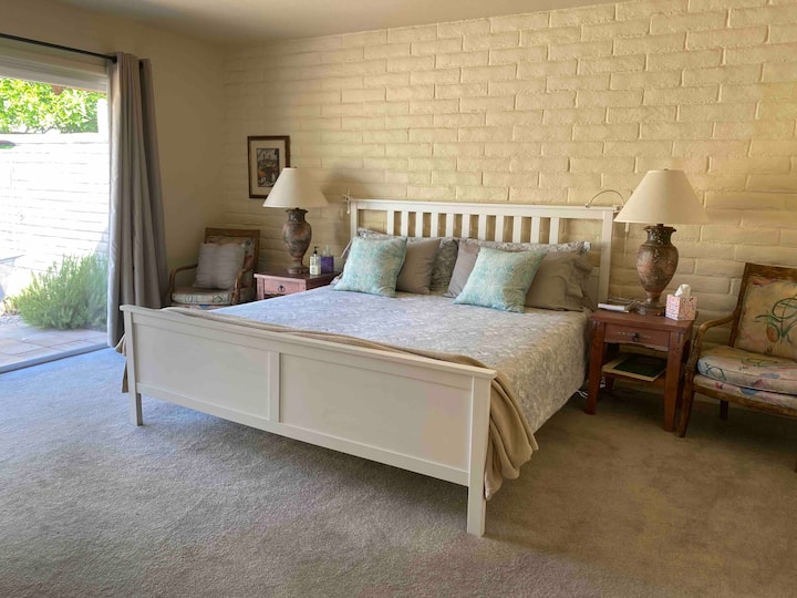 Quarto principal com cama king size e controles deslizantes para o terraço. Mini luzes de leitura em ambos os lados da cama.