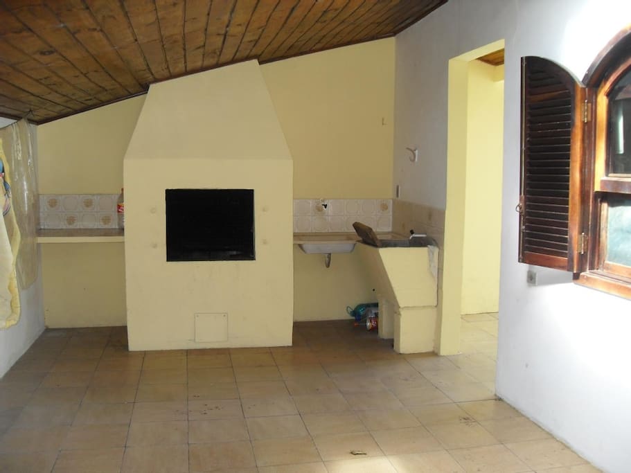 Churrasqueira coberta, com uma mesa de madeira na garagem. (Não aparece na foto).