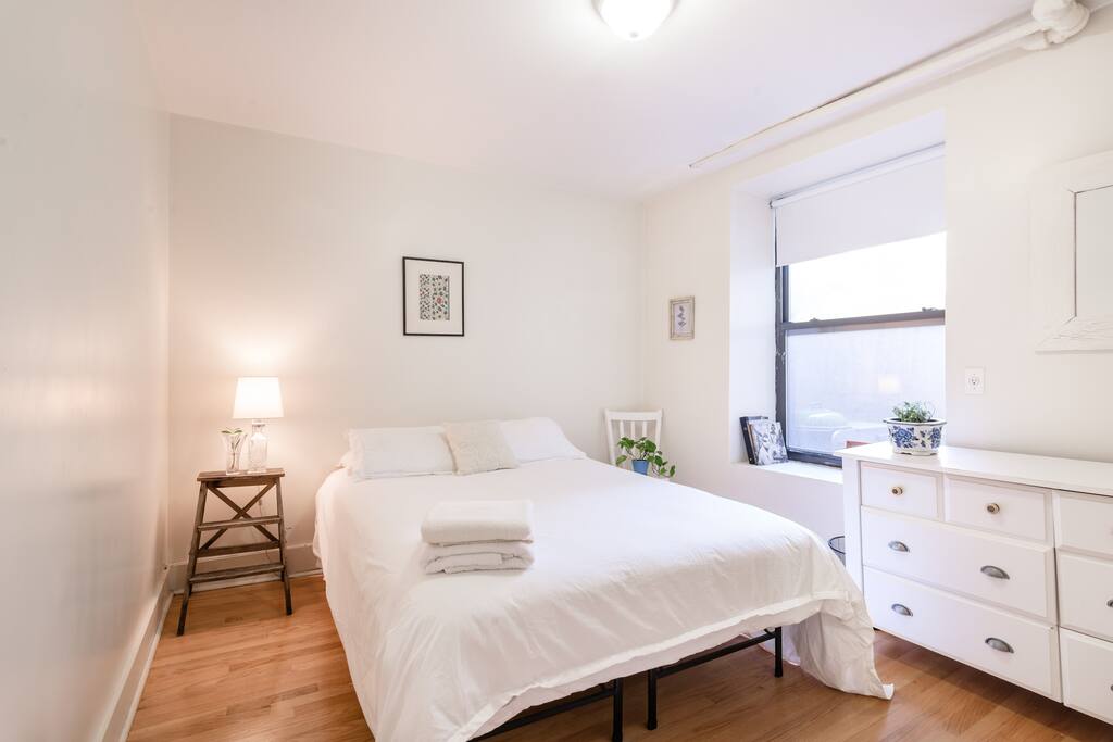 Very large bedroom with full dresser and closet. Apartment overlooks private patio with terra cotta planters and lounge chairs just outside window.