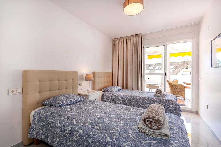 Спалня с две единични легла и плюшени завивки с директен достъп до терасата