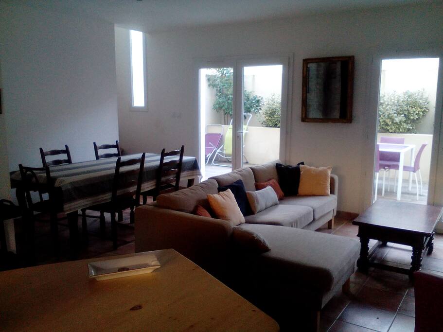 salon et coin repas; on aperçoit la terrasse à l'arrière de la maison