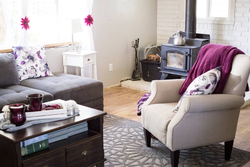 Common Living Room Area, featuring a wood stove, cozy couch, a plethora of blankets, a picture window.