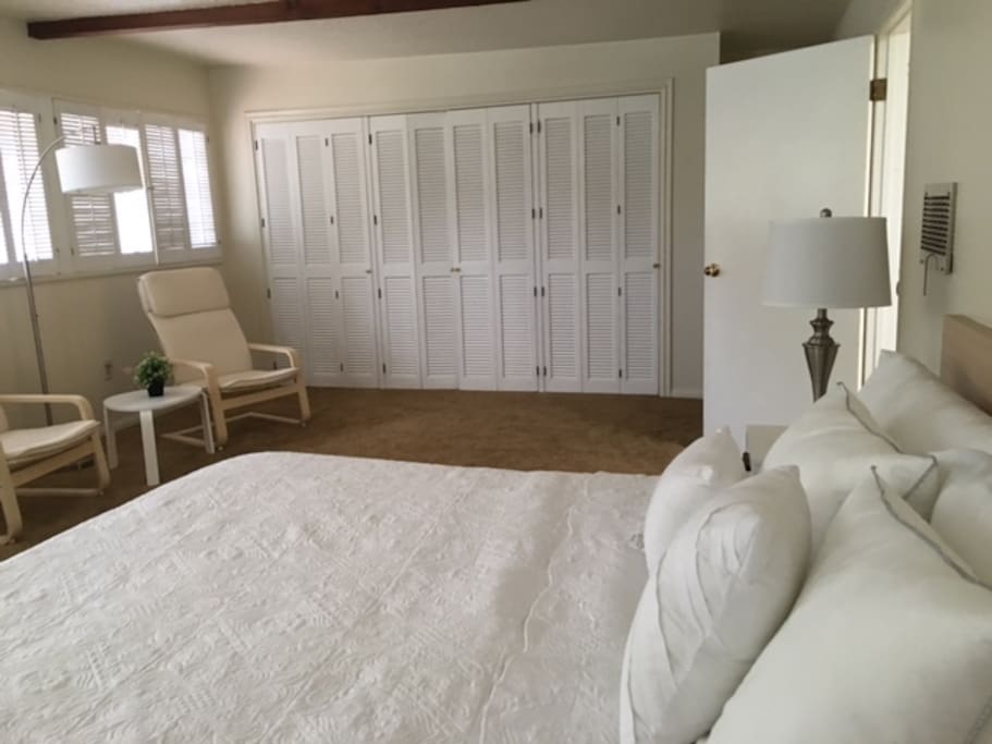 The master bedroom has a new king bed, new bedding, and sitting area, with a spacious red wood closet.