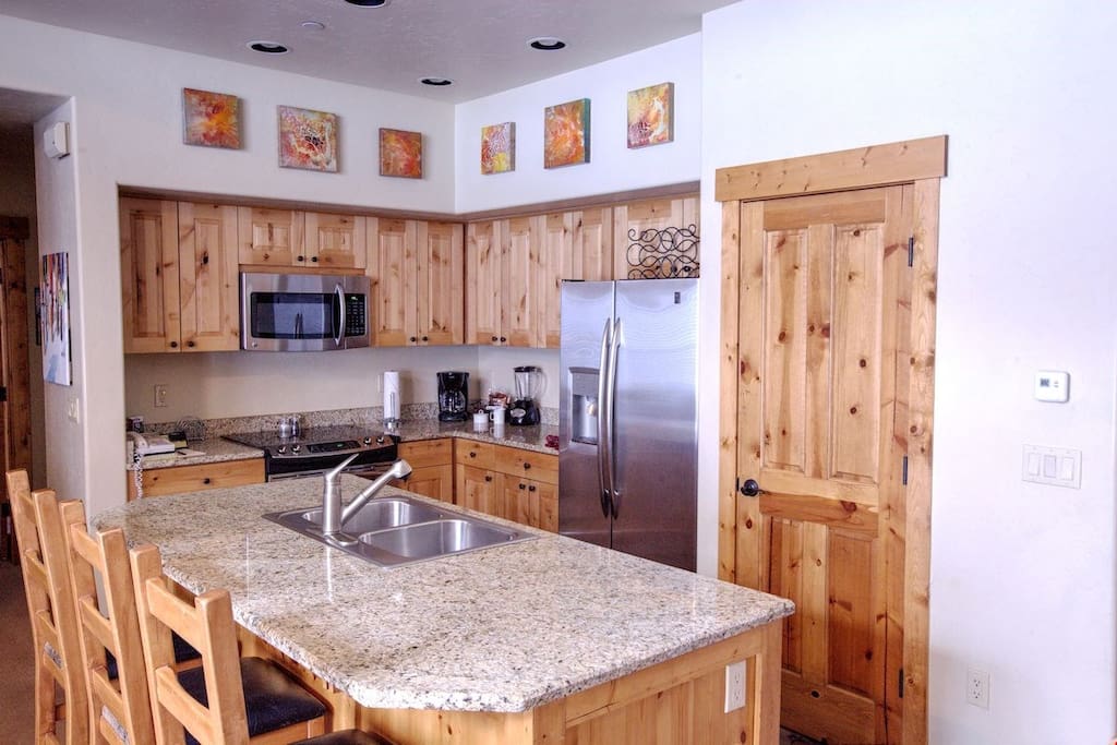 The fully-equipped kitchen features granite countertops, stainless steel appliances and a breakfast bar