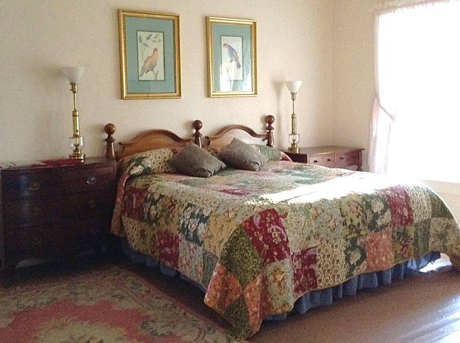 主卧配有一张2米宽双人床、朝西的窗户和通往门廊的门。 