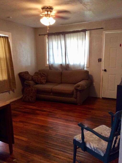 This is a love seat size sofa, but if you remove all the fluffy cushions a petite person (5’2’’ and under) can crash on it ! Extra sheets for it are on the shelf in the bedroom!