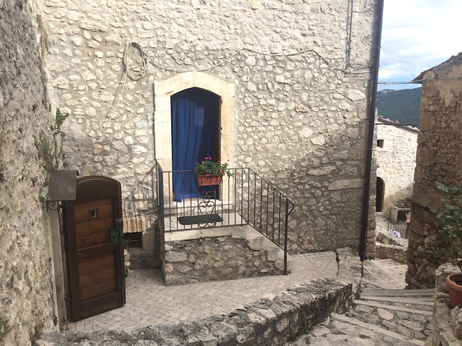 Ingresso della casa con tenda blu, porta di legno ingresso grotta