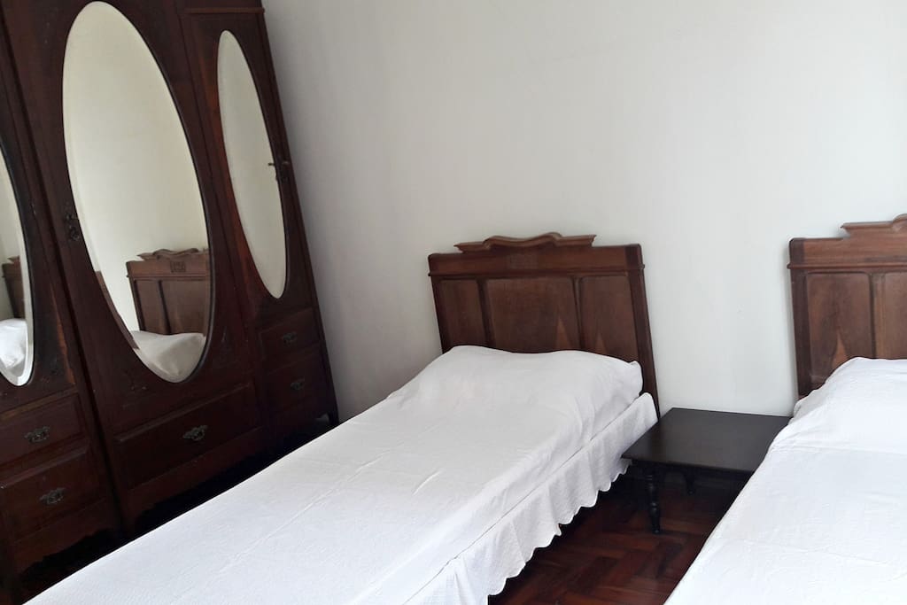 Quarto com duas camas de solteiro, que podem ser unidas para receber um casal, colchão de solteiro para hóspedes extra, ventilador de teto, espaço no armário e chave.