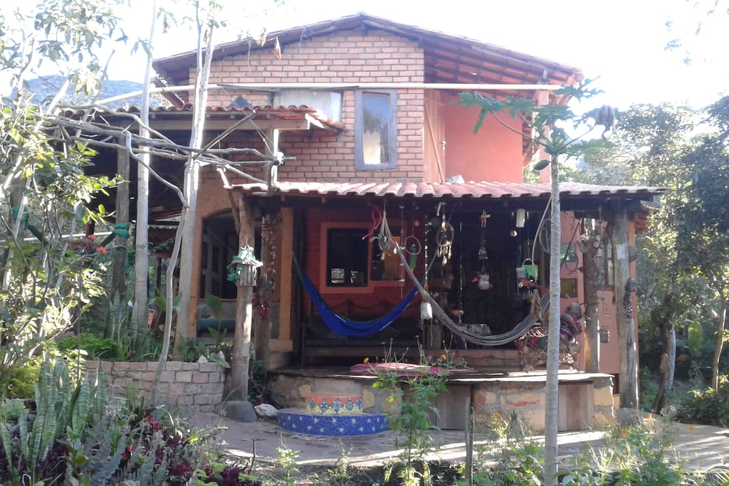 casa vista completa do lado da varanda de madera com foguera no centro y acceso a cocinha semi aberta