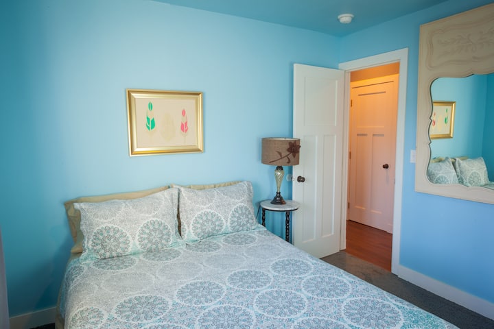 A queen bed in a light filled room