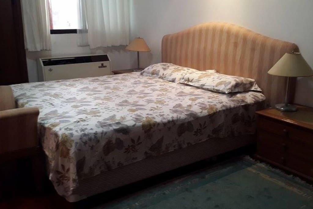 Bedroom with queen sized bed, additional pillows and blankets are available. Room has AC and stand fan. Table for laptop and mirror not seen in this photo.