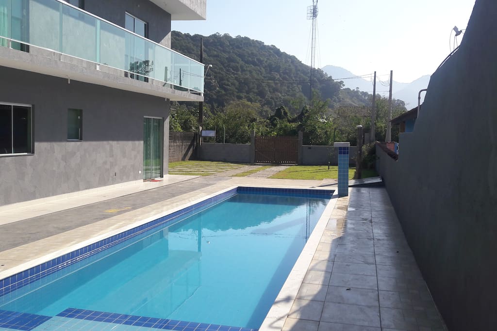 Piscina com cascata, ducha, estacionamento ao fundo.