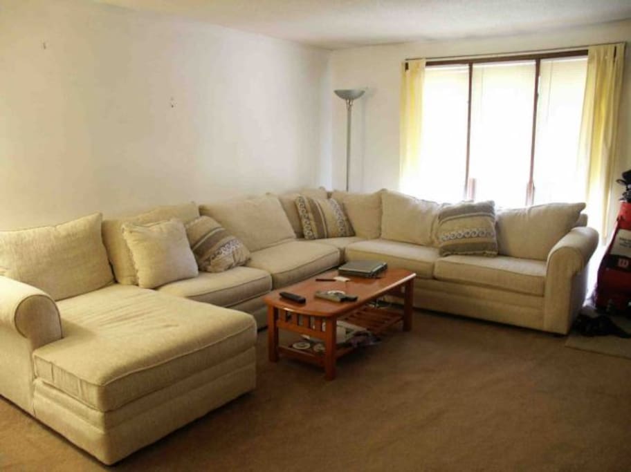 A big spacious living room with a L-Shaped couch to watch TV/movies and just relax.
