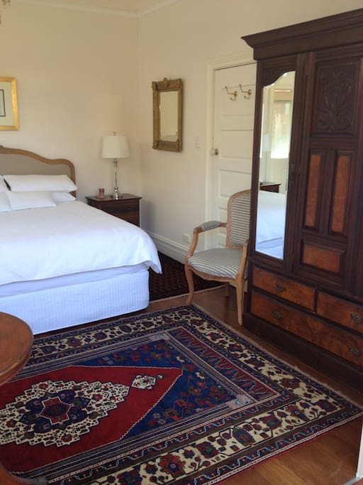 The bedroom with antique wardrobe and Persian carpet.