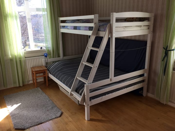 Våningssäng för 3 personer. Den nedre sängen är 140 cm vide och den övre sängen är 90 cm vide. Det finns också en extra gästmadrass.