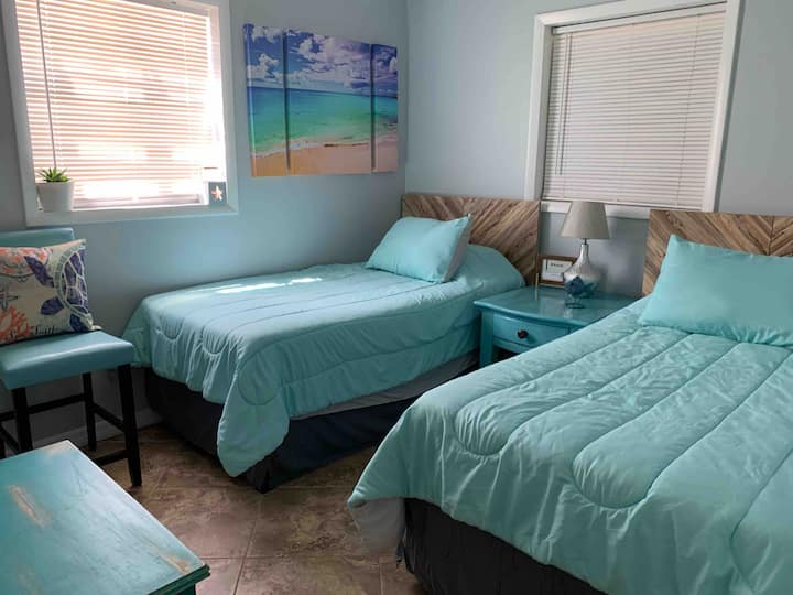 Dormitorio 3: dos camas individuales nuevas, con colchón con tirolina y protectores de almohadas, TV inteligente, mesita de noche y lámpara.