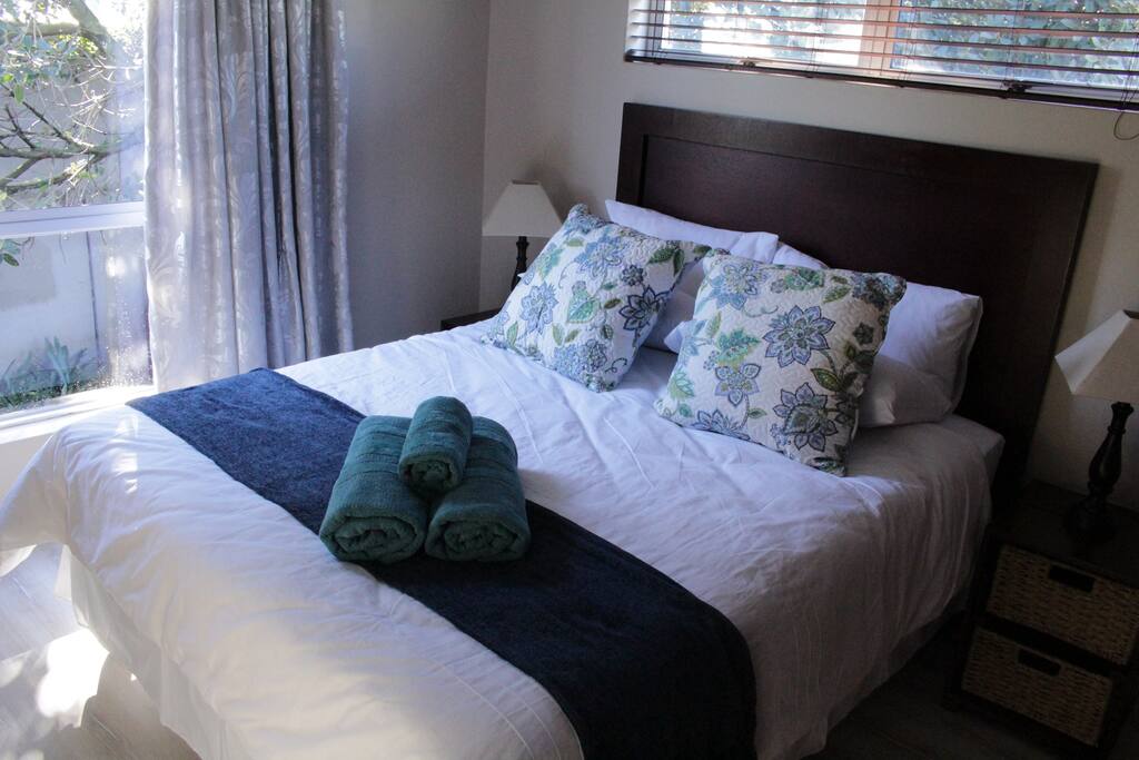 Main bedroom with high quality queen-size bed and dark wood fitted cupboards. Wall fan.