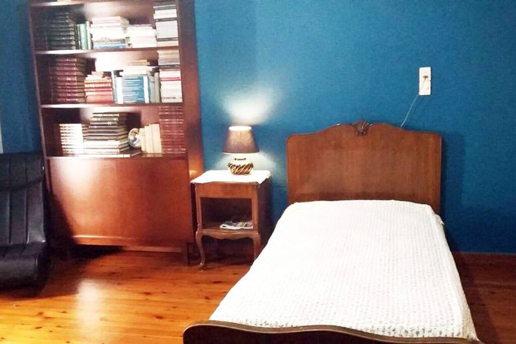 Large bedroom - one twin bed, a bookcase with many interesting books, a bedside table, a desk-workspace and a comfy chair...