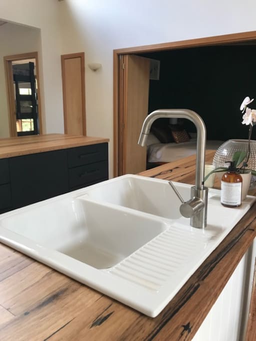 Gentle recycled timber countertops and large ceramic farmhouse sink make the kitchen a joy to use.
