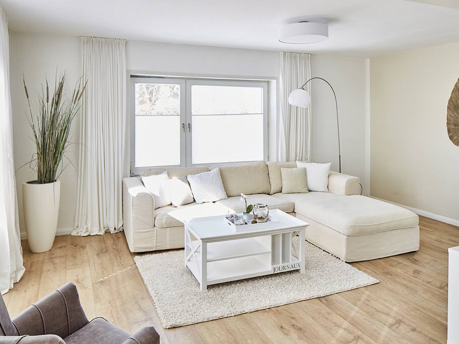 Das Wohnzimmer mit gemütlicher Sofaecke, Zugang zur Terrasse und schöner Einrichtung.